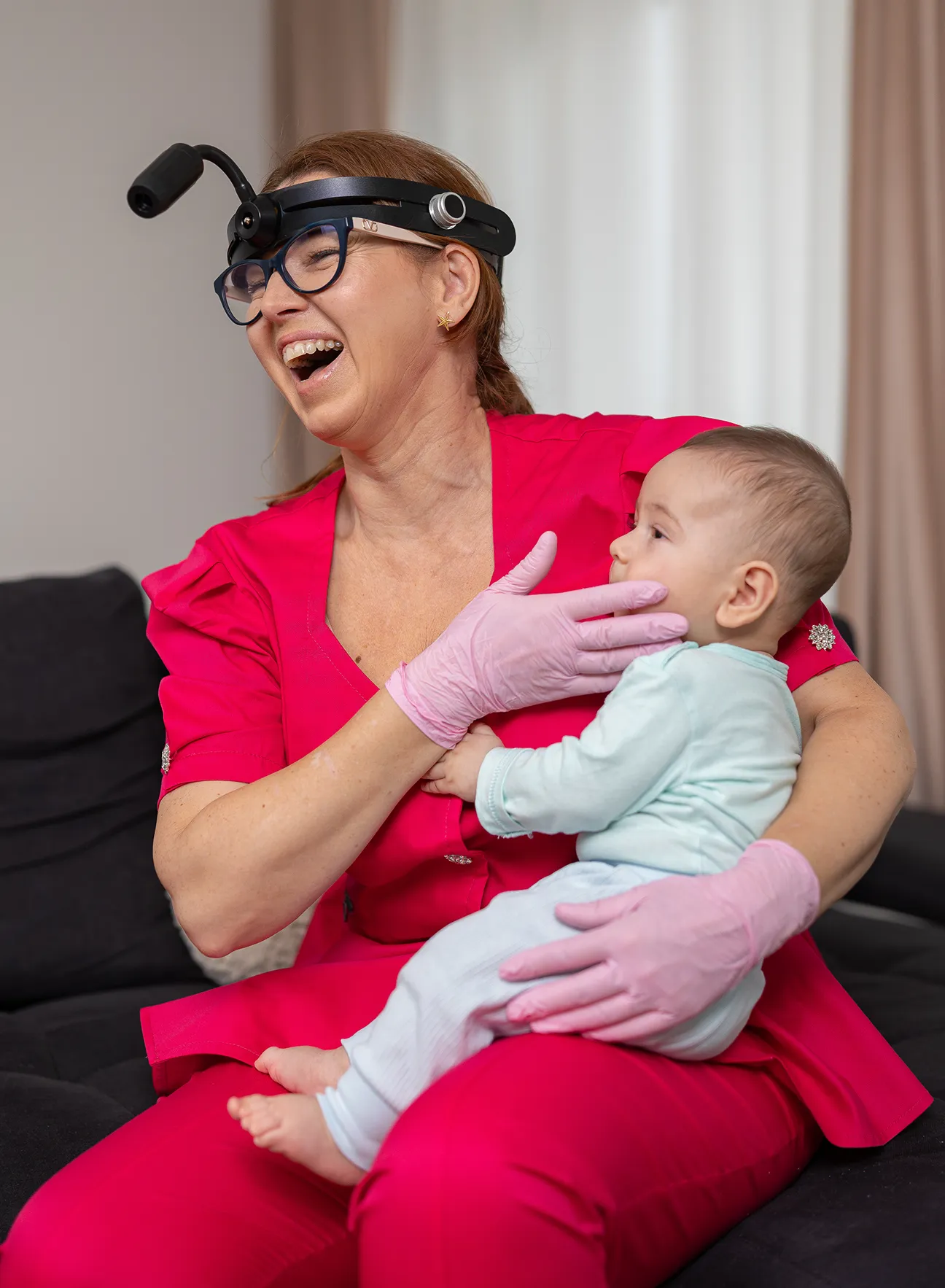 Dr. Cosmina Dușan interacționând calm cu un bebeluș în timpul unei vizite stomatologice pediatrice acasă